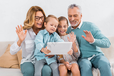 孙辈和祖父母在家里与数字平板电脑进行视频通图片