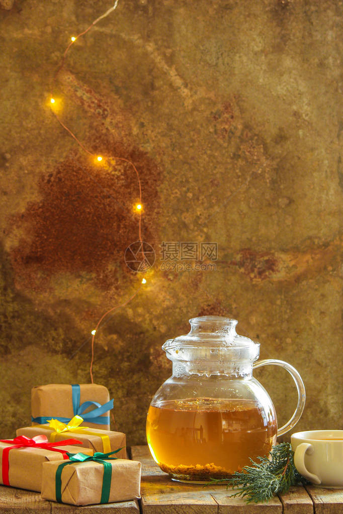 桌子上透明茶壶中的绿色茶叶草药图片