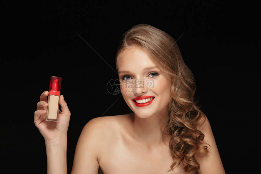 年轻快乐女人的肖像长着卷发和红嘴唇手拿着遮羞霜欢乐地在黑背景上图片