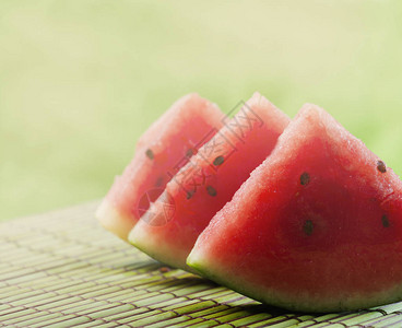 阳光下花园绿桌背景上甜红西瓜片的特写夏季清爽的甜食五颜六图片