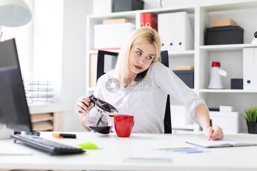 可爱的年轻女孩在明亮的办公室工作这个女孩拿着一个红色的杯子和一个咖啡壶她肩上拿着手机这个女孩有一头白发图片