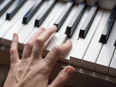 在钢琴键上关闭钢琴家的手指男士手臂演奏音乐或图片