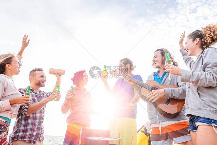 快乐的朋友在海滩上的烧烤时喝啤酒和弹吉他一群年轻人在烧烤派对上一起玩乐和欢笑旅行度假和青年假期的图片