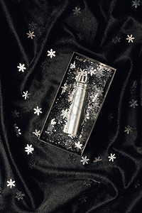 盒子里的香水和黑色织物上闪亮的银色装饰雪花图片