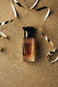闪亮表面的香水瓶和金丝带的顶视图图片
