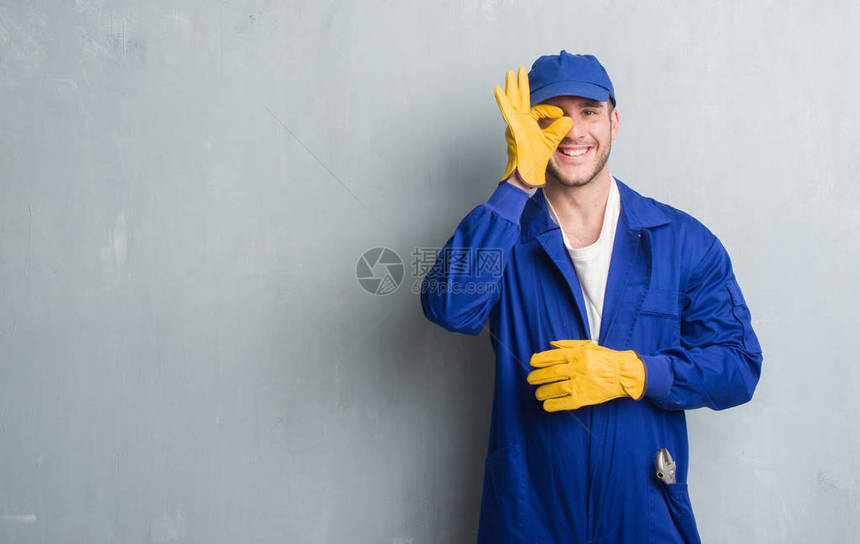 年轻的白人男子在灰色的垃圾墙上穿着机械制服图片