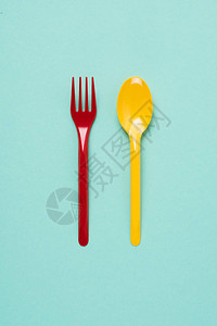 蓝色背景红色塑料叉和黄色勺图片
