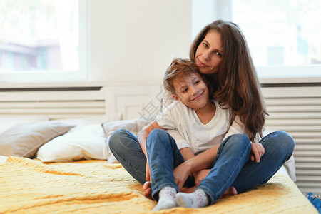 妈和儿子微笑拥抱看着对方握手玩乐坐在家里放松的气图片
