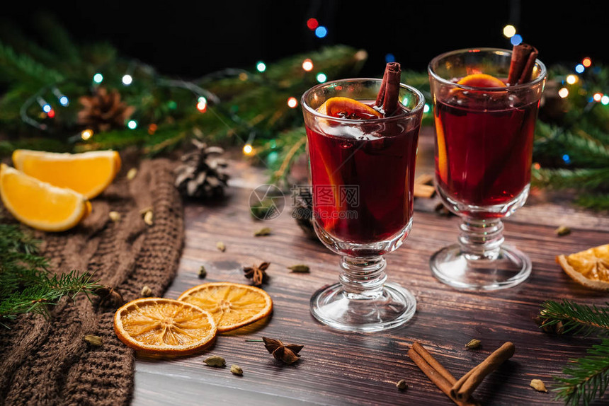 玻璃杯中含橙片肉桂棒和配有圣诞装饰品图片