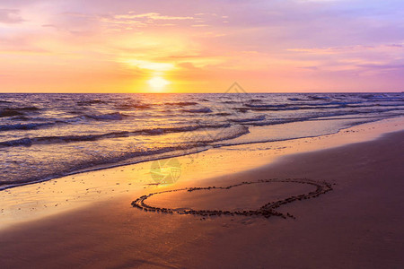 在沙滩上绘制的心形在sunse图片