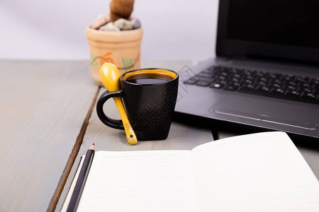 电脑咖啡杯仙人掌和笔记本放在木制办公室桌面上图片