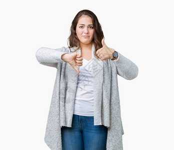 美丽的大码年轻女子穿着冬季夹克在孤立的背景下做大拇指上下图片