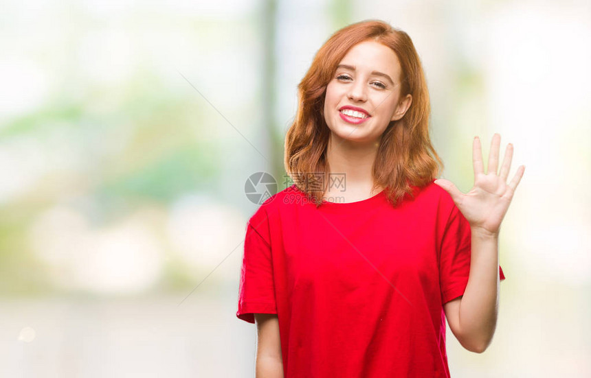 年轻美丽的女人在与世隔绝的背景展示并用五指向上面微笑着自信图片