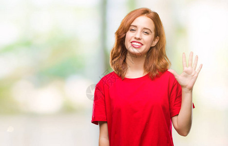 年轻美丽的女人在与世隔绝的背景展示并用五指向上面微笑着自信图片