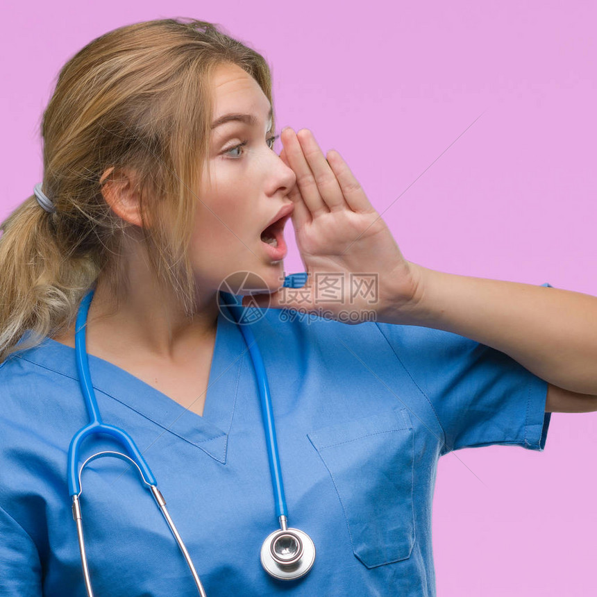 身穿外科医生制服的年轻白人医生女人在孤立的背景下大喊叫图片