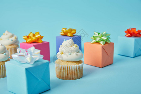 蓝色背景中的美味纸杯蛋糕和五颜六色的礼物图片