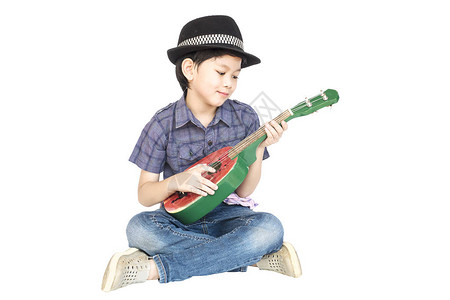 尤腾青年7岁的亚裔男孩坐着玩乌鲁列琴在白背景