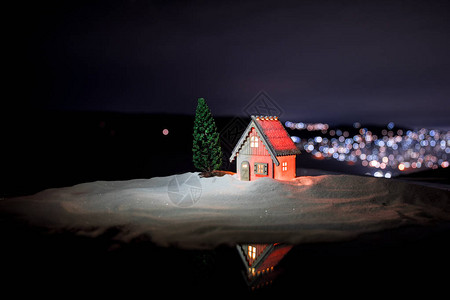 晚上在雪地里的圣诞节和新年微型房子与枞树图片