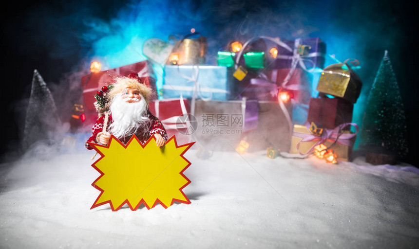 或圣诞假期购物概念店铺促销圣诞老人拿着黄色贴纸为您在雪地上的文字堆在图片