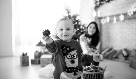 男孩在圣诞树节庆园和礼品盒的下玩耍黑白形象笑声图片