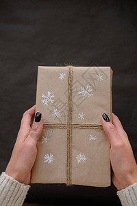 女人拿着黑色背景的圣诞盒礼物女双手带着寒假的礼物圣诞节新年购物假期准背景图片