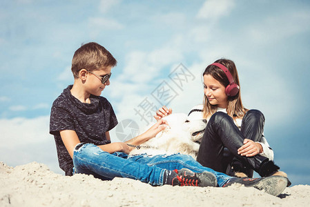 男孩和女孩在海边度假快乐的11岁男孩在海边他的狗品种萨摩耶图片