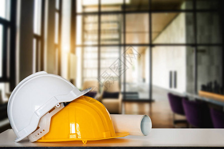 建筑房屋和建筑修理工程建筑图纸和白桌上的头盔图片