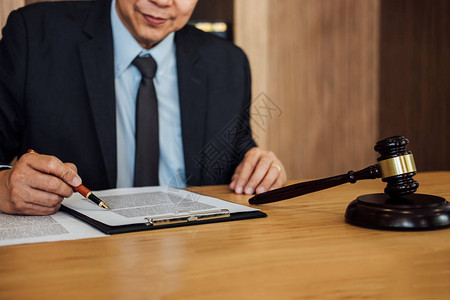 木桌上的木槌和律师或法官在法庭主题司法和律概念图片
