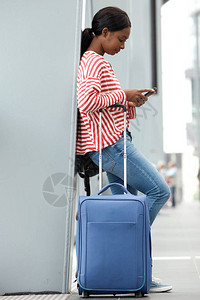 在机场带手提箱旅行的年轻女子全长侧面肖像图片