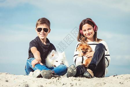 男孩和女孩在海边度假快乐的11岁男孩在海边他的狗品种萨摩耶图片