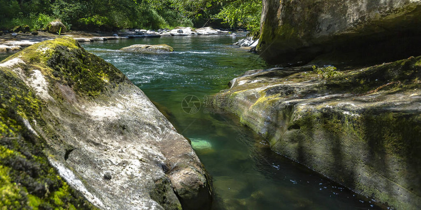 在阳光明媚的森林里的岩石小溪上流动的水图片