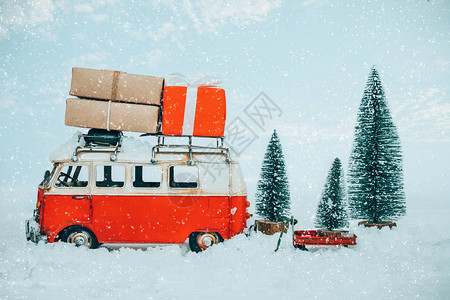 复古圣诞明信片微型古董车在下雪的冬季森林的屋顶和圣诞树上携带礼背景图片