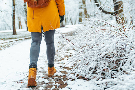 妇女走在下雪城市公园从后面看背图片