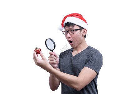 戴着眼镜和灰色衬衫的亚洲圣诞老人男子正在寻找和寻找一个红色礼品盒图片