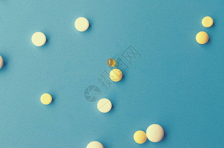 蓝色背景上的混沌散落的白色和黄色药丸图片