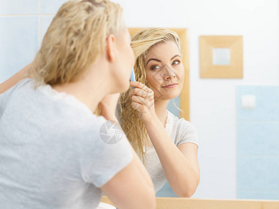 年轻美人照顾发型洗完淋浴后梳湿的金图片