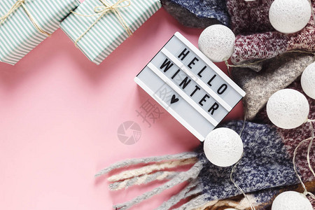 温暖舒适的冬装围巾灯箱和圣诞装饰品作为柔和粉色背景的框架图片
