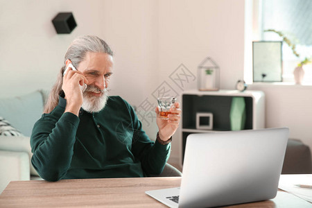 老人在家用电话聊天时喝酒威士背景图片