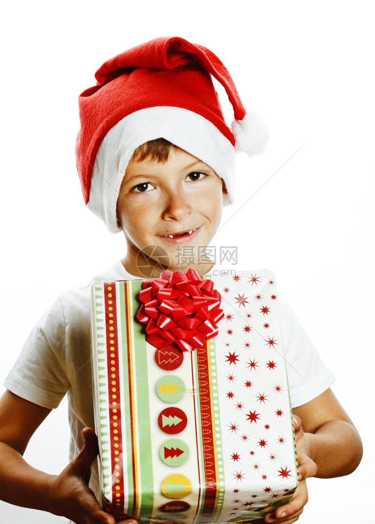 穿着圣塔红帽子的年轻漂亮男孩孤立在白色持有礼物盒图片