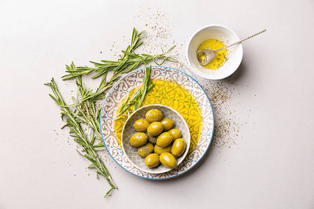 浅色背景下橄榄油和迷迭香的组合物图片