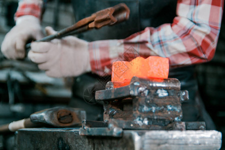 铁匠工作空间铁匠与红热金属工件一起工作的铁匠在Anvi图片