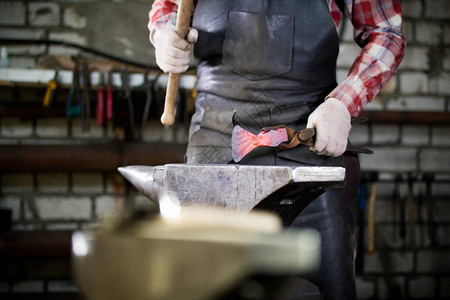 铁匠在锻造的铁砧上用的红色热金属工件作专注于手图片