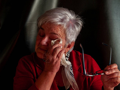 一位老妇人哭着用手帕擦眼泪图片