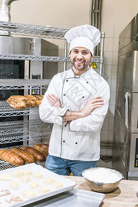 男面包师微笑的男子面包师站在厨房时手举着图片