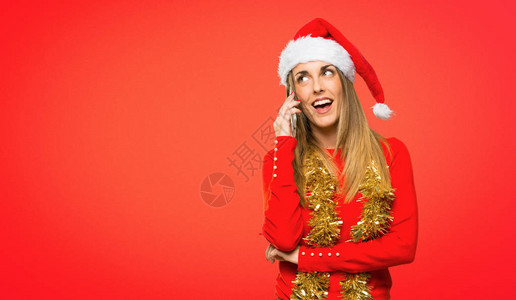 为圣诞假期打扮的金发女郎与红色的人用手机通话图片