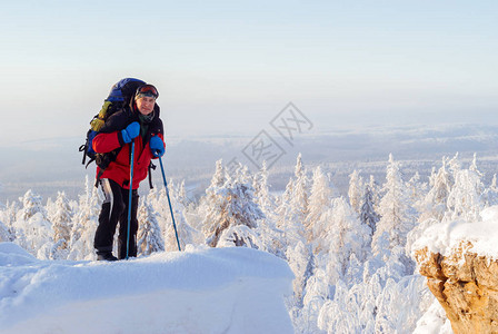 男徒步者背着包爬上雪覆盖的山峰图片
