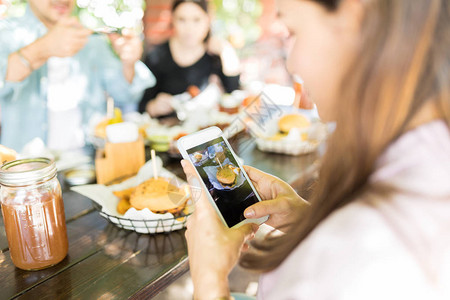 在智能手机上拍摄诱人汉堡以上传到社交媒图片
