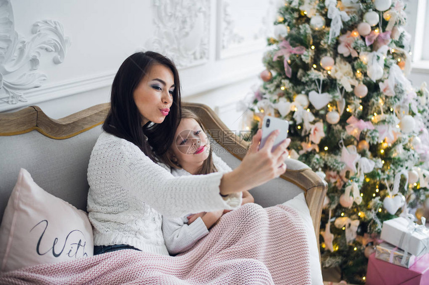 快乐的时髦的母亲和女儿有一棵小圣诞树现在图片