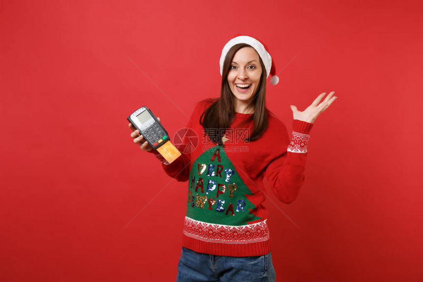 快乐的年轻圣诞老人女孩拿着无线现代银行支付终端来处理和获取信用卡支付图片