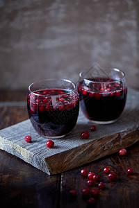 两杯自制的热葡萄酒和小红莓放在厨房的木架上图片